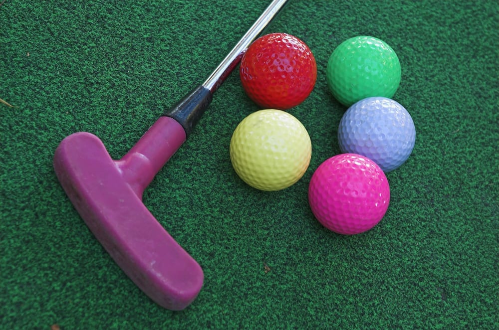 A mini golf putter and 5 colorful golf balls