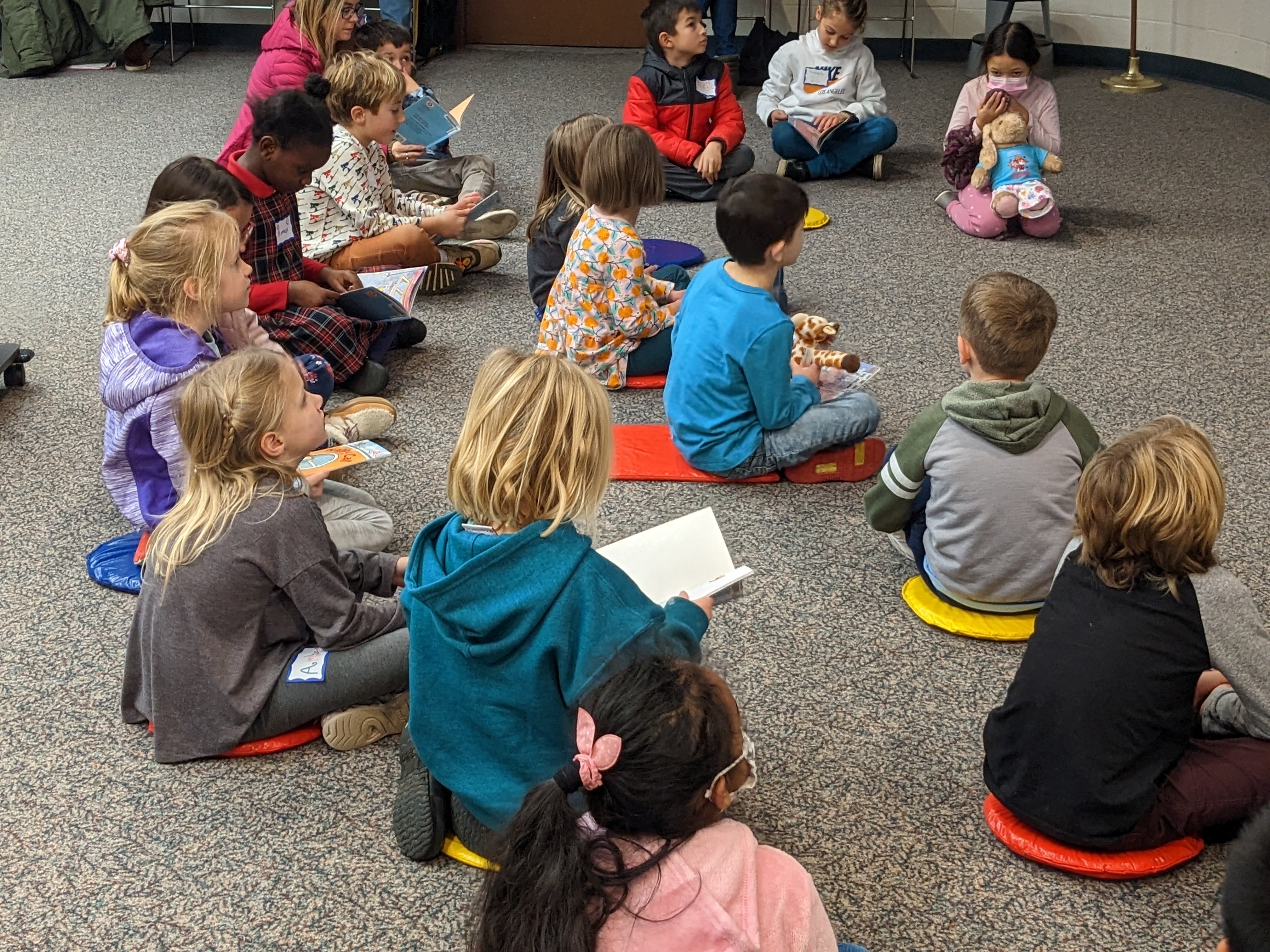 a group of children sitting on the floor reading books