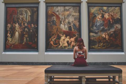 Woman sitting in gallery looking at paintings