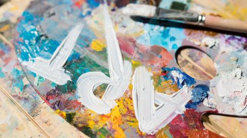 A messy paint palette with the word 'Art' written in white paint. 
